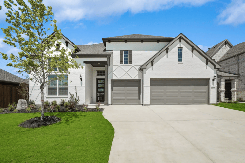 Two-story home exterior with a three-car garage and a manicured front lawn