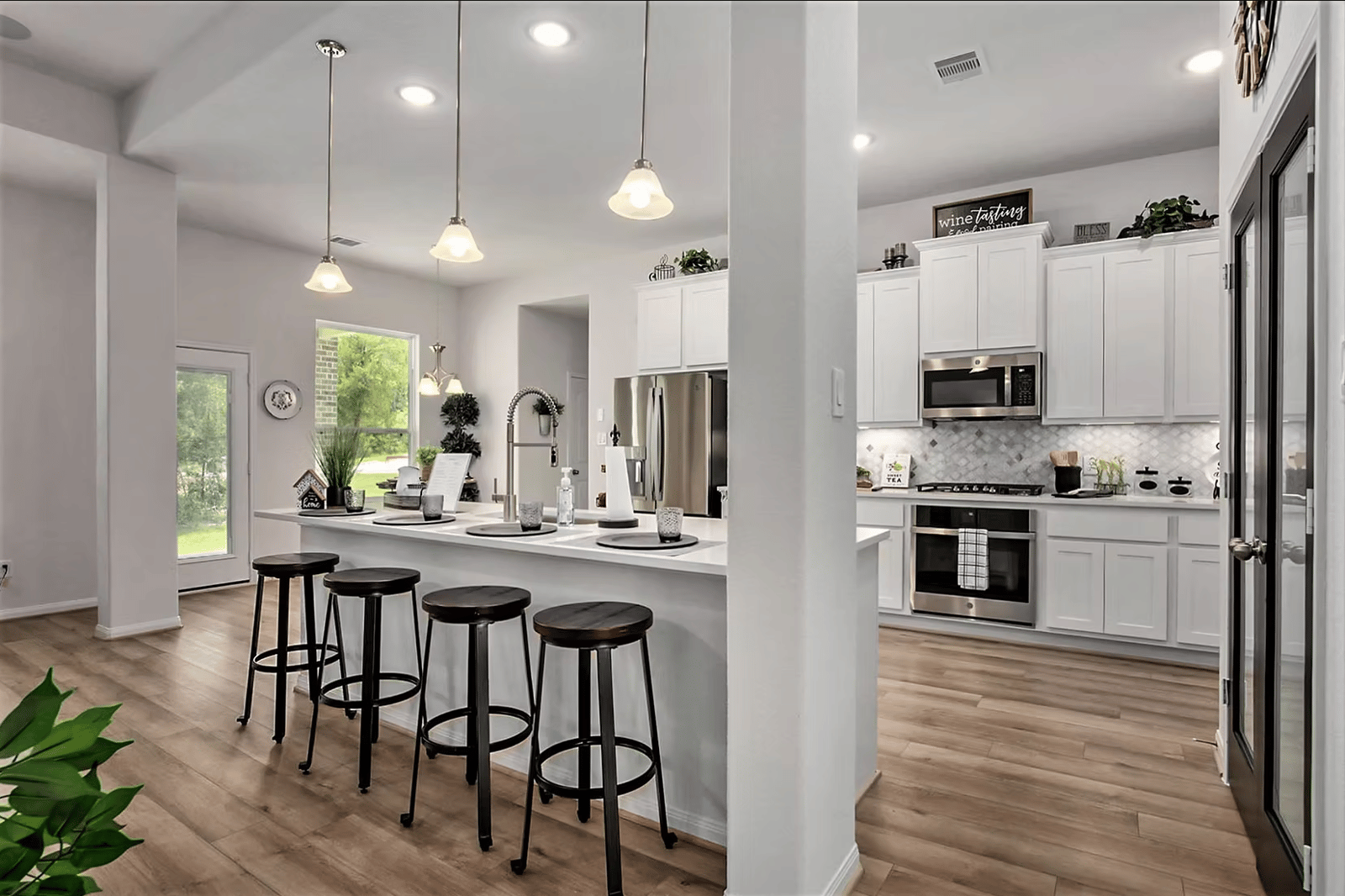 Kitchen island with counter stools, pendant lighting and stainless steel appliances