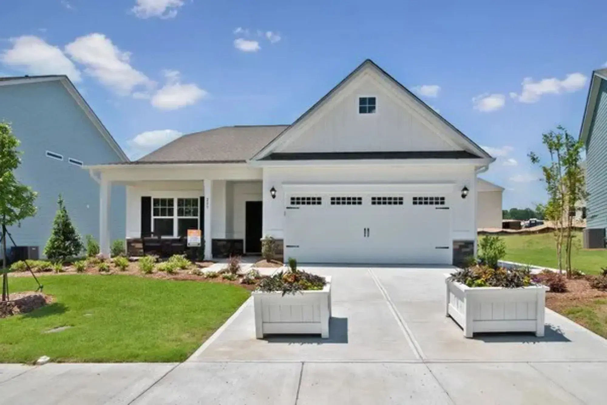 Single-story new-construction home with a board-and-batten gable, covered front porch, stone accents and a two-car garage