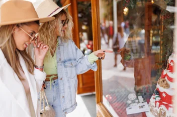 Two shoppers pausing at a boutique window display