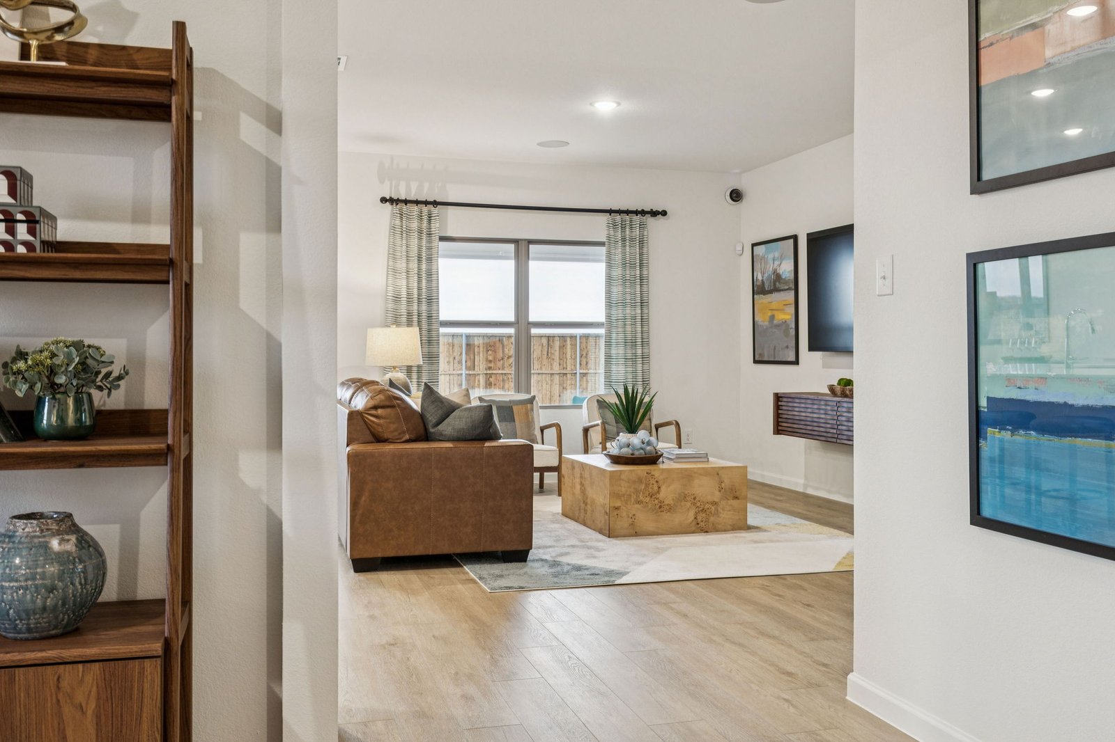 Flex living space with tall wood shelving, a sofa and a wall-mounted television
