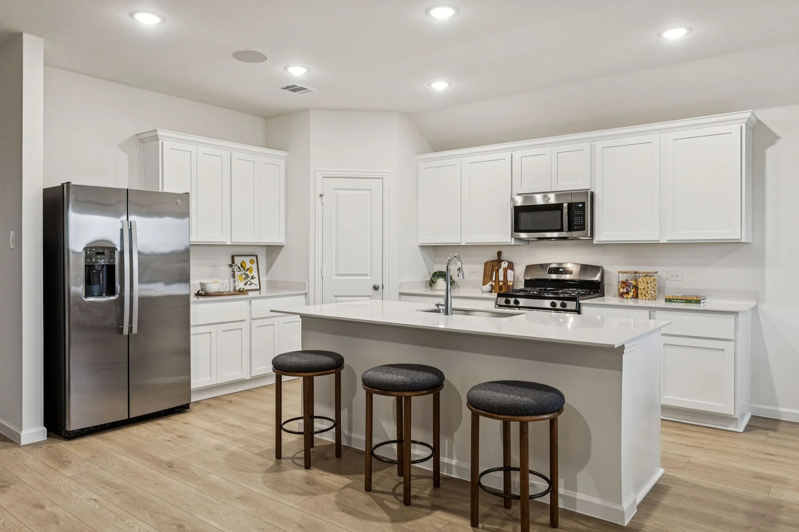 Kitchen with a center island, counter stools and a stainless steel refrigerator