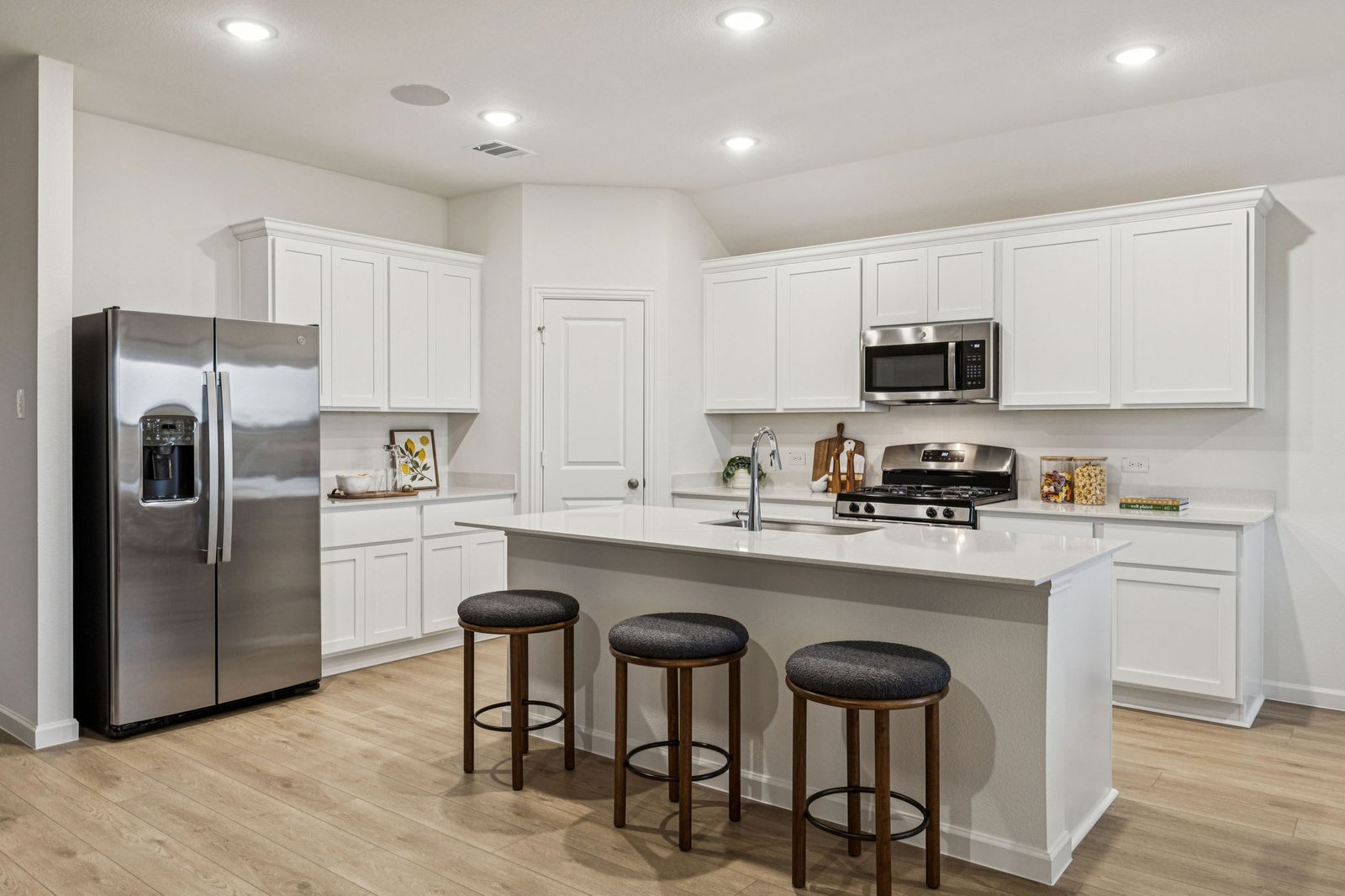 Kitchen with a center island, counter stools and a stainless steel refrigerator