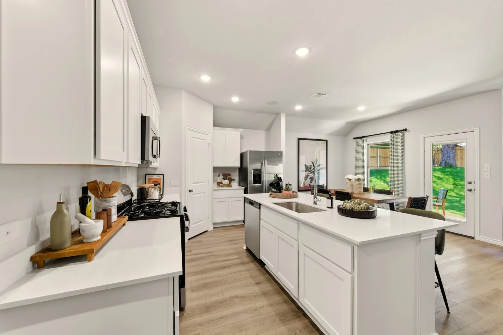 Kitchen with an island sink and gas range, opening onto a dining nook with a door to the backyard