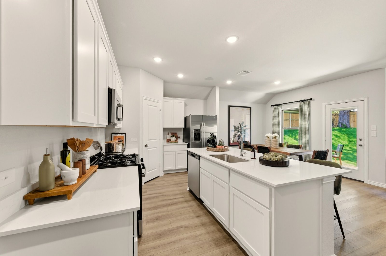 Kitchen with an island sink and gas range, opening onto a dining nook with a door to the back garden