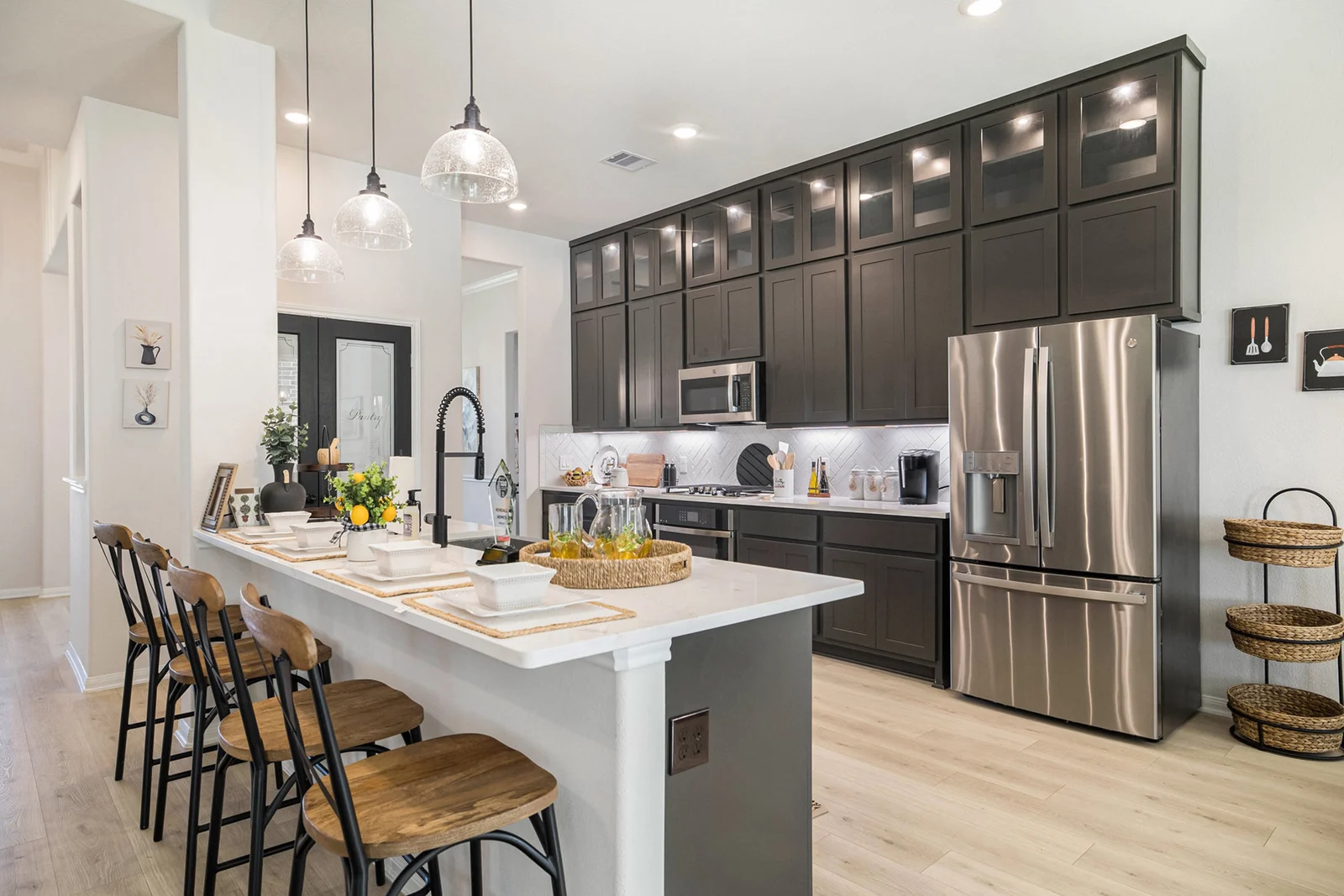 Kitchen with dark shaker cabinets, a white quartz island with four barstools and stainless appliances