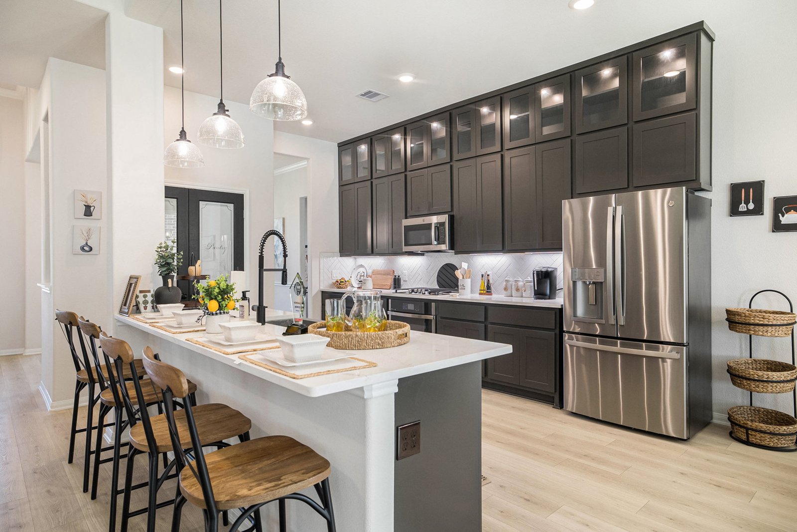 Kitchen with dark shaker cabinets, a white quartz island with four barstools and stainless appliances