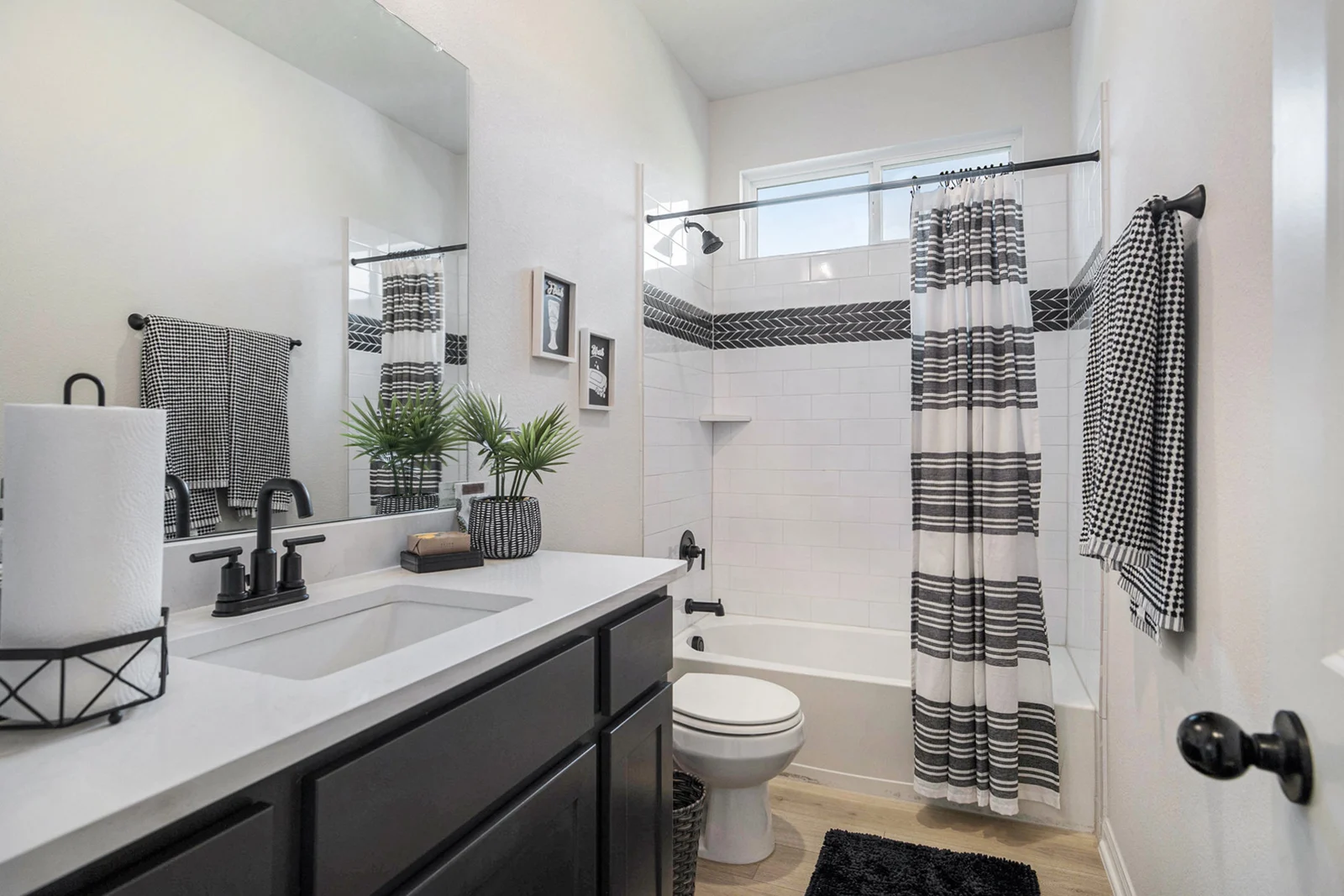 Secondary bathroom with a shower-tub combination, striped curtain, dark vanity and patterned towels
