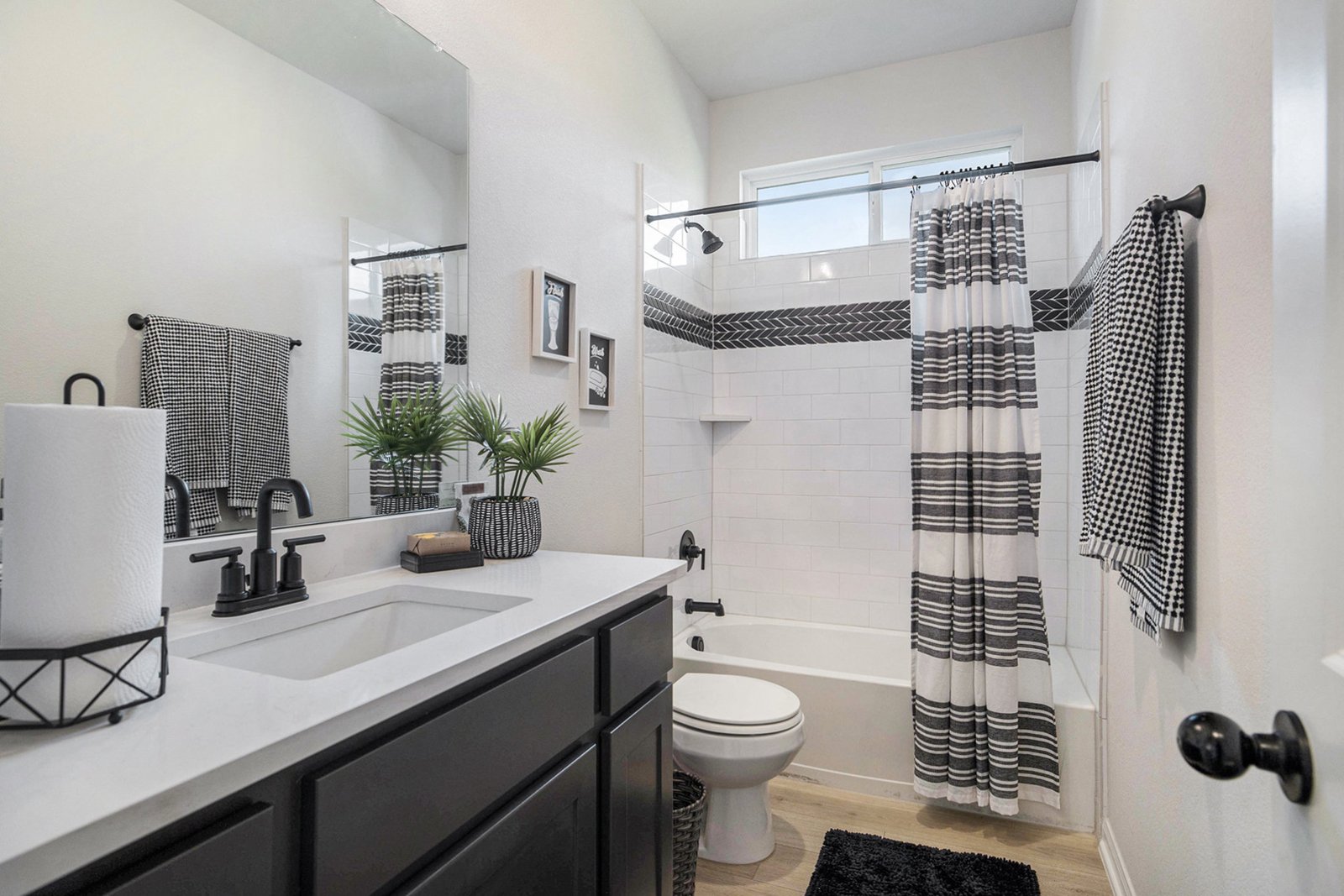Secondary bathroom with a shower-tub combination, striped curtain, dark vanity and patterned towels