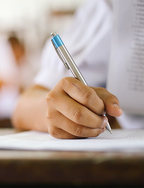 Student writing with a pen on lined paper