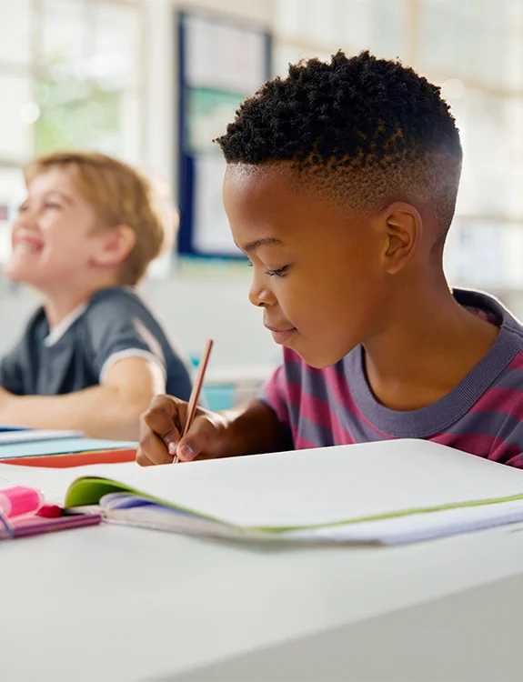 Two students working side by side at a classroom desk