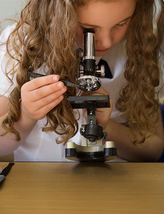 Student looking through a microscope during a science class