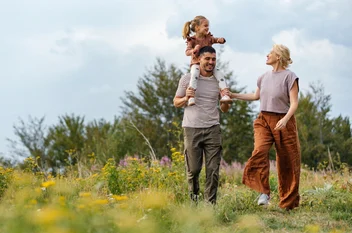 Family walking through a wildflower meadow, a child riding on a man's shoulders