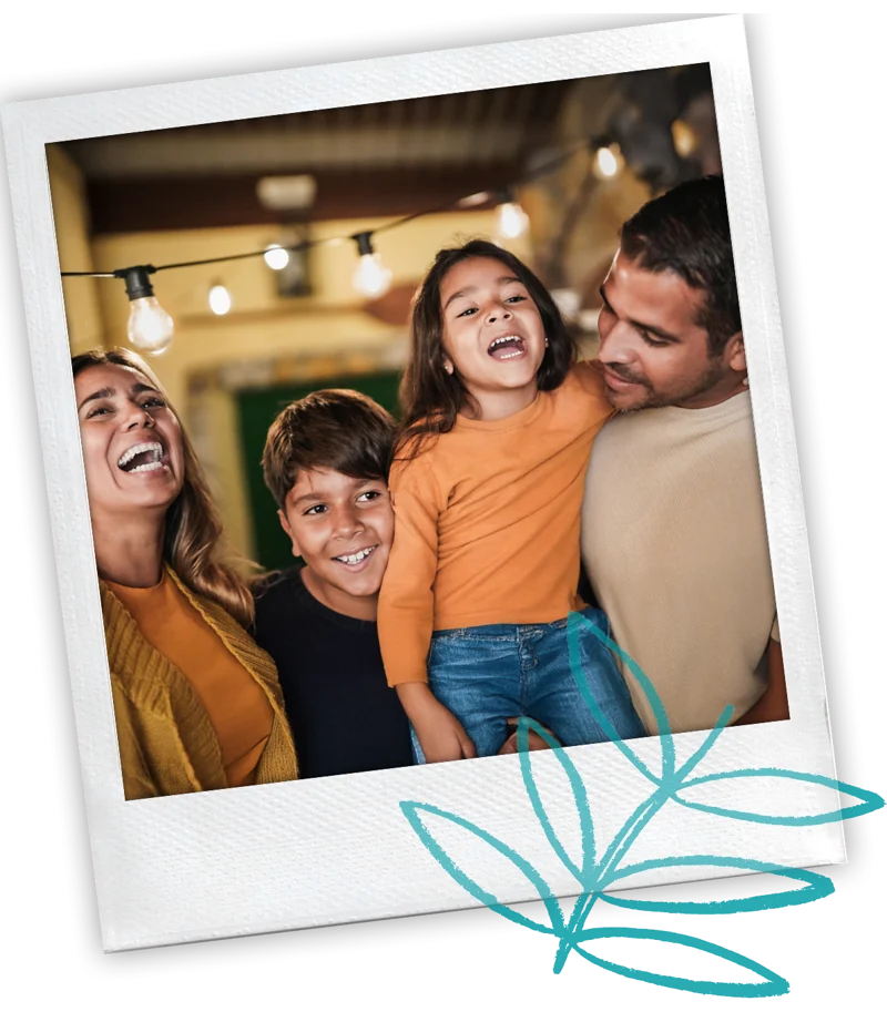 Polaroid-style photo of a family of four laughing together under string lights