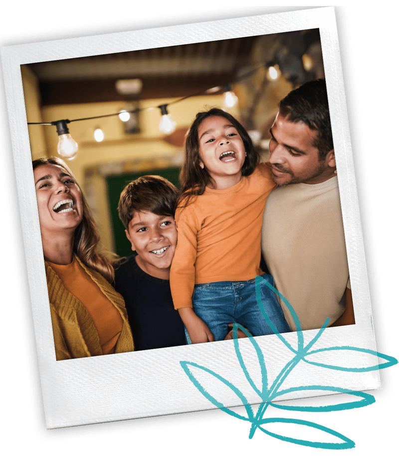 Polaroid-style photo of a family of four laughing together under string lights