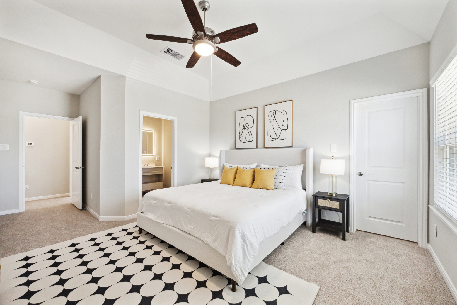 Main bedroom with an upholstered wing bed, mustard cushions, line-drawing prints and an en-suite doorway