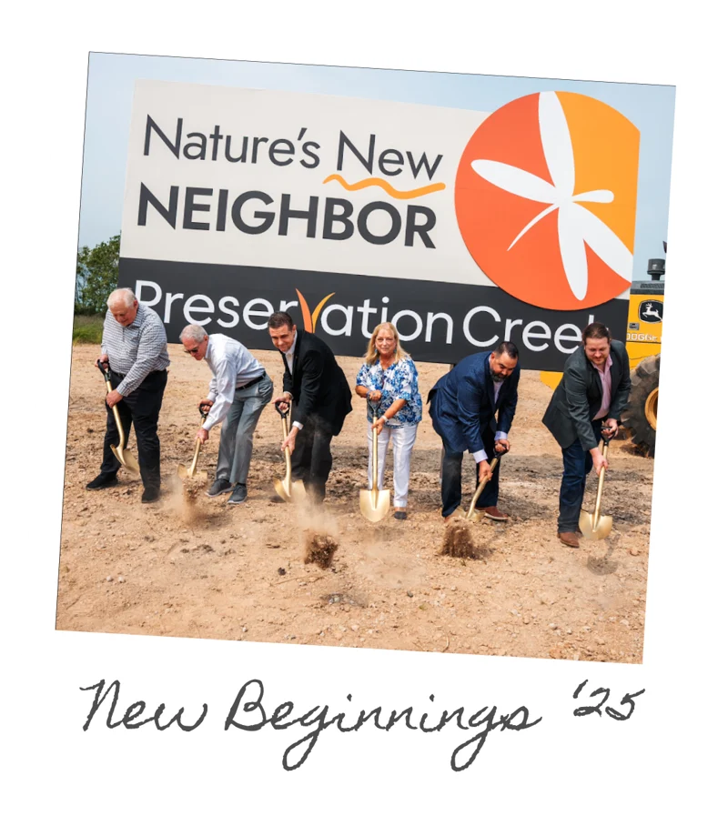 Groundbreaking: six people turning soil before the Nature's New Neighbor site sign, captioned New Beginnings '25