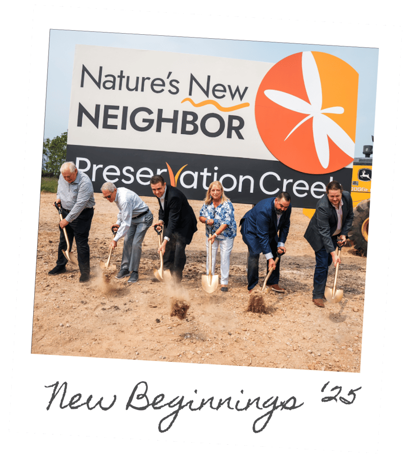 Groundbreaking: six people turning soil before the Nature's New Neighbor site sign, captioned New Beginnings '25